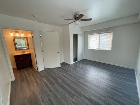an empty living room with wooden floors and a ceiling fan
